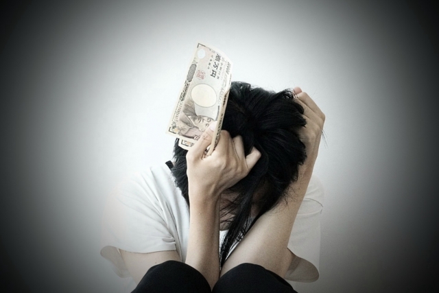 お金を手に頭を抱える。曽於市で債務整理の無料相談ができます